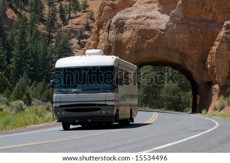 Class A RV recreational vehicle driving past natural red rock tunnel
