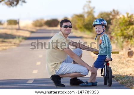smiling cute boy with a balance bike spending fun time together with his handsome father