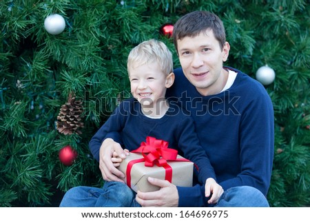 cheerful smiling boy and his father with gift box at christmas time