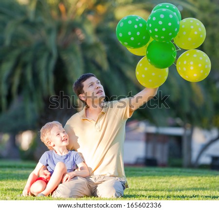happy family of father and his son with colorful balloons