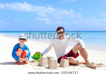father and son building sand castle at the tropical beach