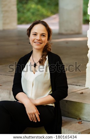 Pretty young female tourist sitting on stairs of old building with columns.