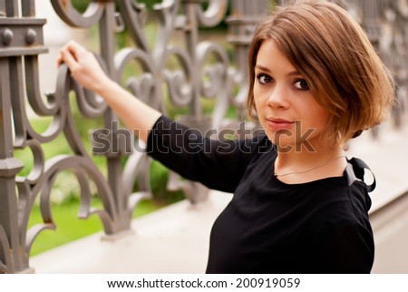 Pretty woman in summer dress outdoors 	 stick on fence.