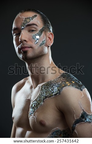 Young handsome man with  mosaic body art, standing in front of black background: body-art project