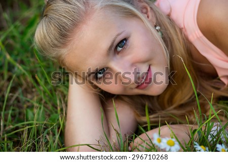 A happy laughing young woman laying on the grass and looking into the camera.