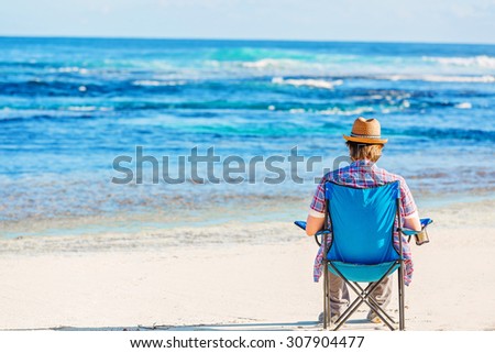 Young man freelancer resting on a chair on the beach