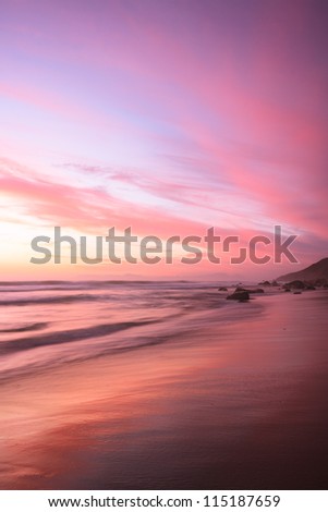 Pink sunset reflects on the beach