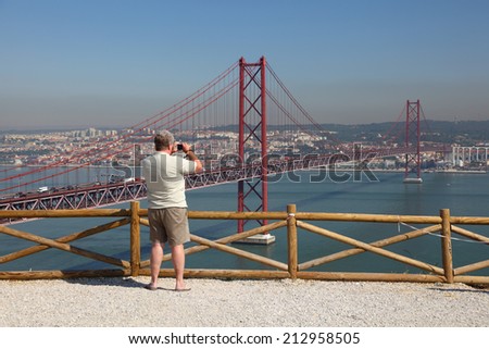 LISBON, PORTUGAL - JUNE 30: Tourist taking pictures of the Ponte 25 de Abril - Suspension bridge over the Tagus river. June 30, 2010 in Lisbon, Portugal