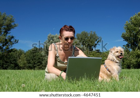 Senior woman with laptop and dog in a park