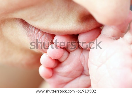 Mother kissing her little newborn baby's feet