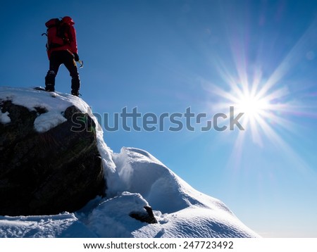 Mountaineer standing at the top of the mountain. Sunny winter day. Italian Alps, Europe.
