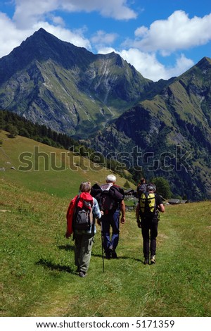 Trekkers walking along a mountain path, west Alps, Italy.