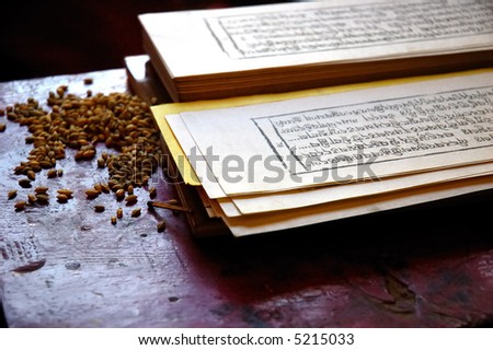 Close up photo of a traditional tibetan prayer book, with seed of grain used during the religion rituals.