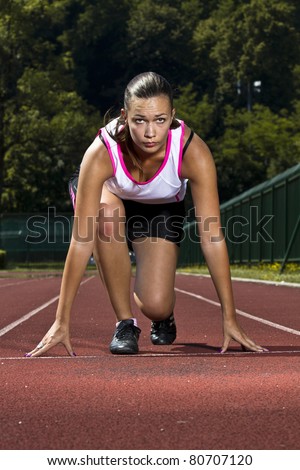 Young woman in sprinting position on the track