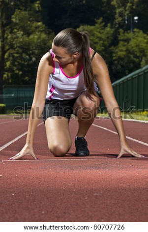 Young woman in sprinting position on the track