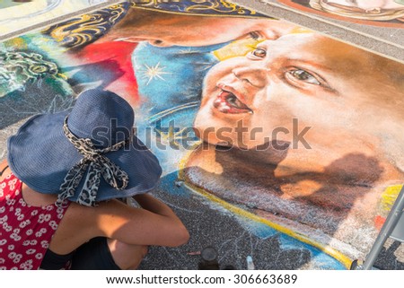 Curtatone, italy 15/08/2015: pavement street artist finishes painting over the asphalt in Madonnari word competition in italy of chalk paintings, from Santuario della Beata Vergine delle Grazie,