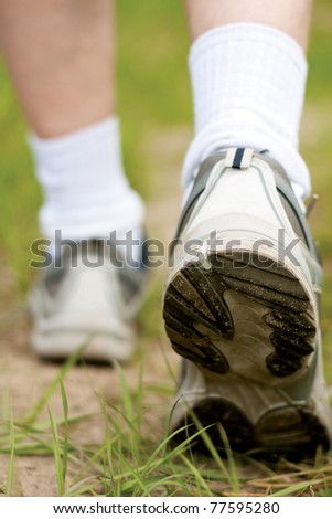 Man walking on hiking trail in forest, sport shoe closeup