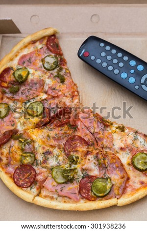 pieces pizza with sausages and bacon in pasteboard box with tv remote control