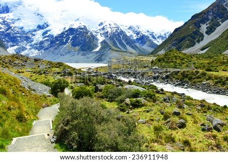 Boarded trail section in Hooker Valley on a track leading to Aoraki, Mount Cook, highest peak of Southern Alps, an icon of New Zealand partially covered in clouds
