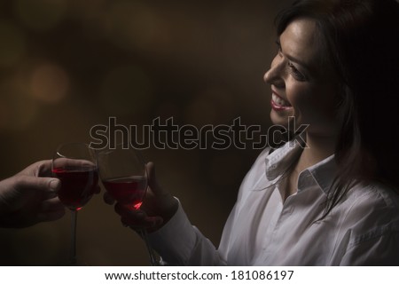 Beautiful girl with a glass of red wine toasts with her date