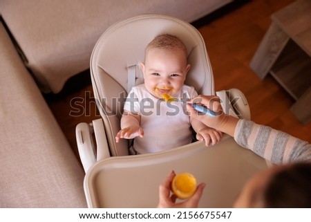 Similar – Image, Stock Photo Cheerful mother feeding adorable baby