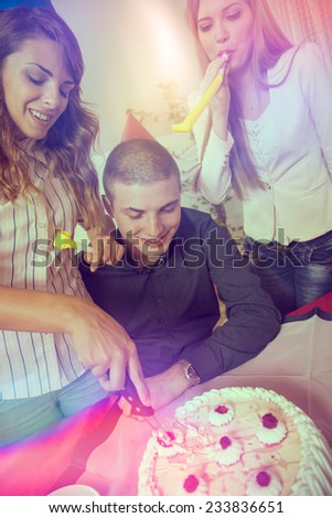 Three young people celebrating a friend\'s birthday and cutting a birthday cake