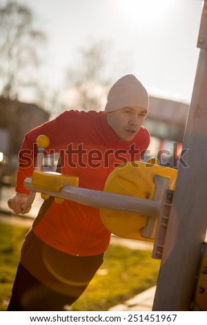 Young athlete working-out in an outdoor gym. Soft focus
