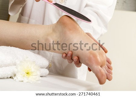 Beautician taking care of female client\'s foot giving pedicure treatment