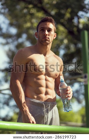 Muscular built young athlete working out in an outdoor gym