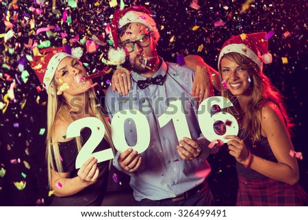 Three young friends having fun at New Year\'s Eve Party, holding cardboard numbers 2016