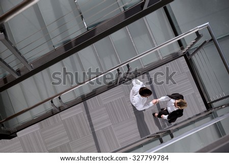 Top view of confident businessman and woman shaking hands in an office building lobby
