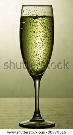 Glass of sparkling wine on yellow background