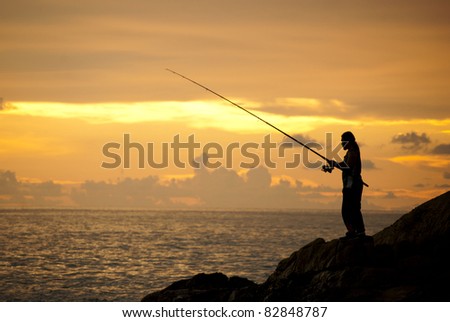 a man is fishing in evening and gold sunset background