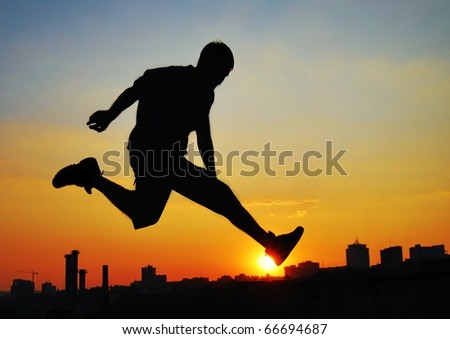 Jumping man on the background of the city at sunset