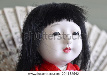 Japanese geisha doll with dark hair in a dress.