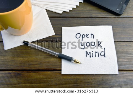 Open your mind, think positive -  handwriting on a napkin with a cup of coffee