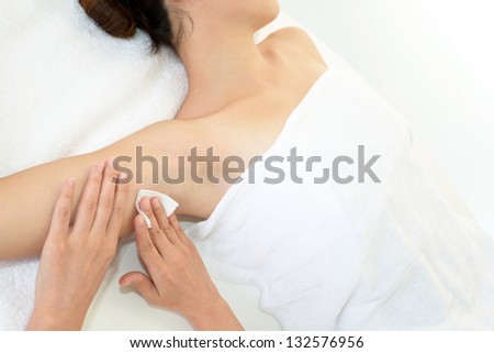 Beautician waxing woman\'s armpit at spa salon