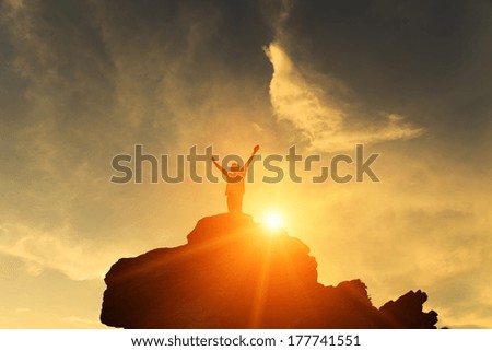 Silhouette of the person on the high rock at sunset
