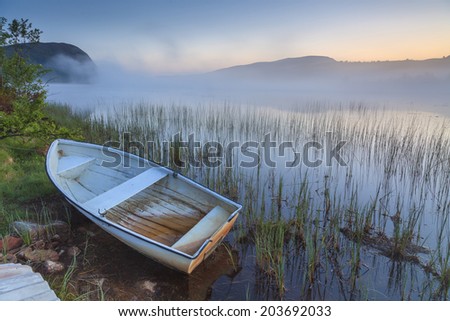 View on foggy lake with boats on the shore. Norway.