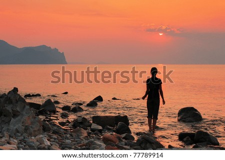 The girl on the beach watching the sea sunrise