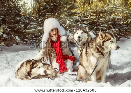 A portrait of beautiful woman with three dogs in the winter forest