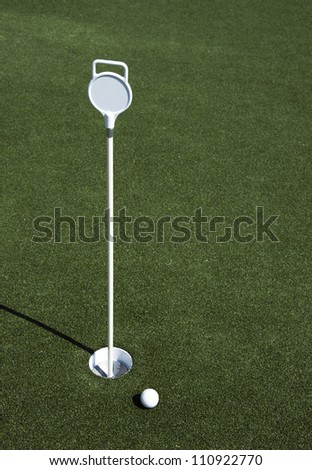 A golf ball sits near the hole on the putting green