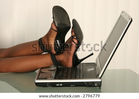Office worker rests legs on laptop in office
