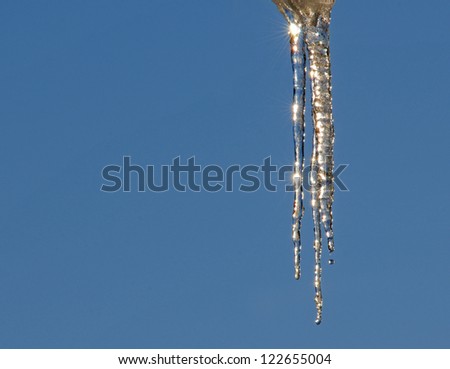 Winter border: cluster of sparkling icicles against blue sky