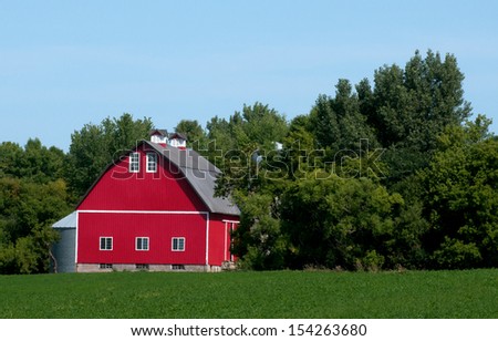 Bright red barn with green field and green trees