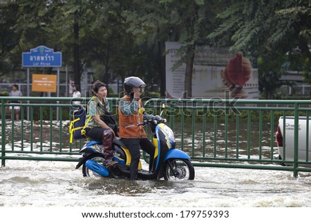 BANGKOK, THAILAND - NOVEMBER 5: A man and women rides a motorcycle through the water during the worst flooding in decades in Bangkok\'s Central plaza ladprao , Thailand on November 5, 2011.
