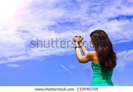 young women formed a heart with her hands in the sky