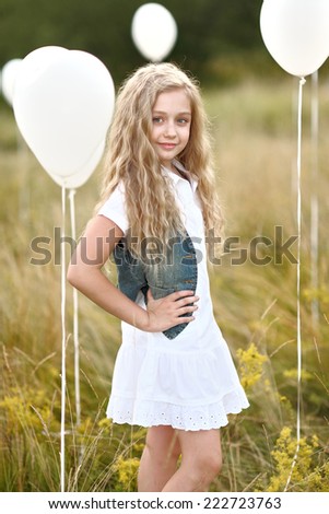 portrait of a little girl in a field with white balloons