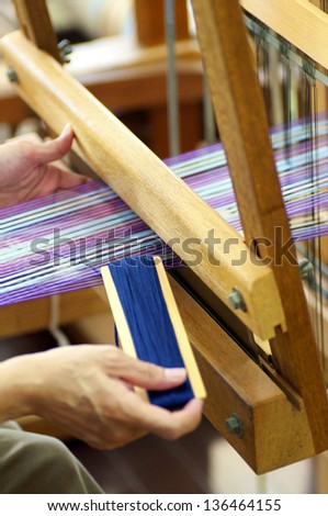 Woman working on a traditional, manual loom, weaving.