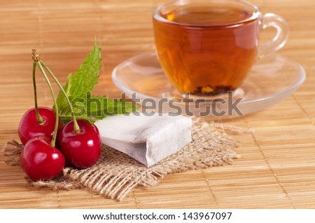 Fruit tea(tea package) in cup with cherry
